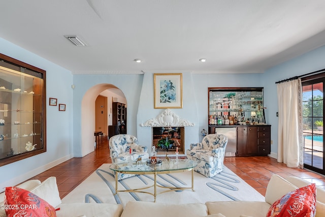 tiled living area with arched walkways, baseboards, visible vents, and a bar