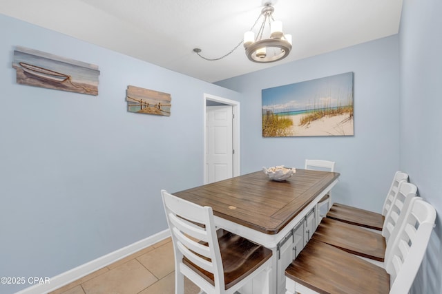 dining space with a chandelier, baseboards, and light tile patterned floors