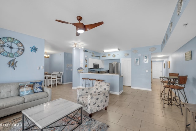 living room featuring a ceiling fan, light tile patterned flooring, and baseboards