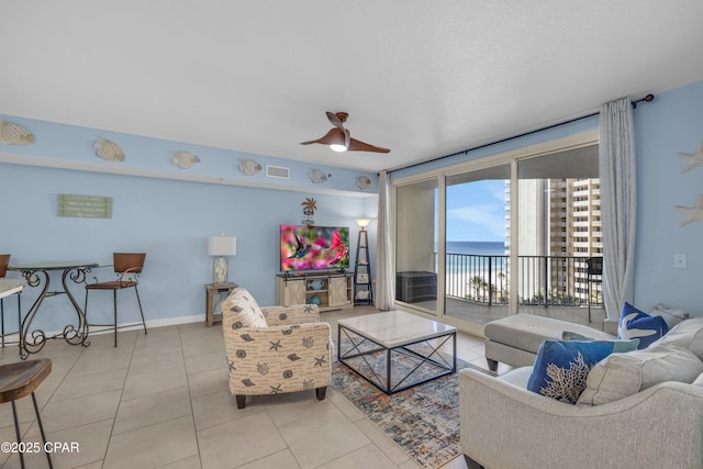 tiled living room featuring expansive windows, visible vents, a ceiling fan, and baseboards