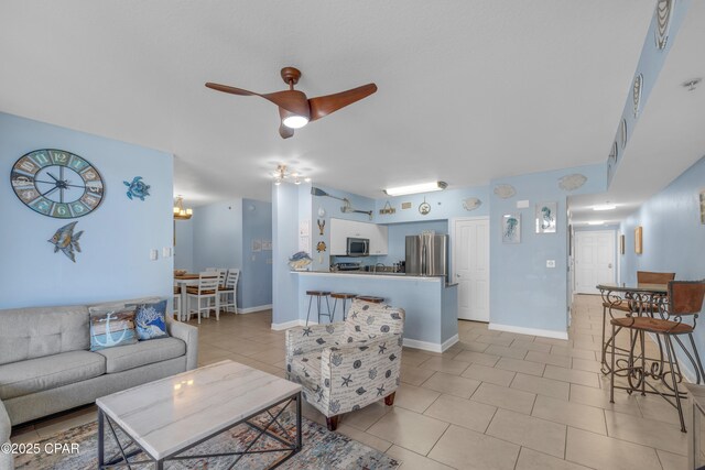 living area with light tile patterned flooring, ceiling fan, and baseboards