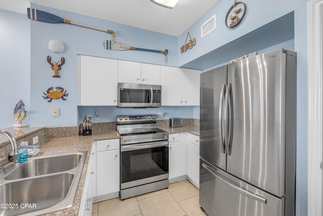 kitchen with light tile patterned floors, a sink, visible vents, white cabinetry, and appliances with stainless steel finishes