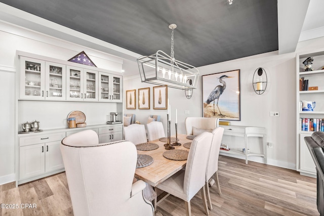 dining room featuring light wood finished floors, baseboards, and a notable chandelier