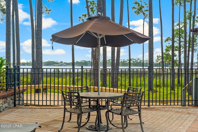 view of patio with fence and a water view