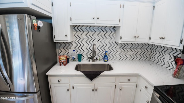 kitchen featuring white cabinets, freestanding refrigerator, and decorative backsplash