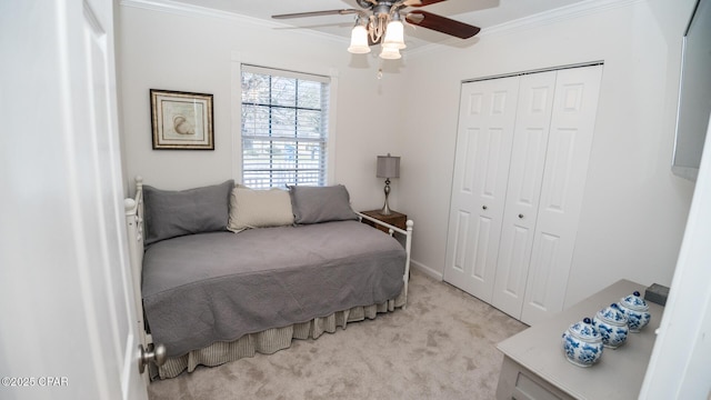 bedroom featuring light carpet, ceiling fan, ornamental molding, and a closet