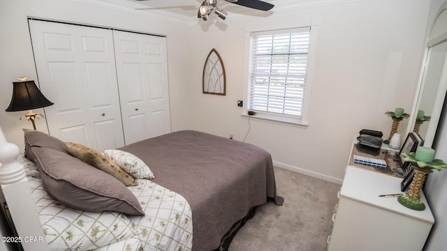 carpeted bedroom with baseboards, a closet, a ceiling fan, and crown molding