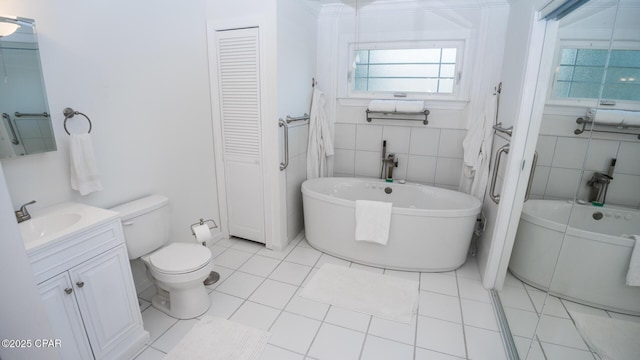 full bath with a closet, toilet, tile patterned flooring, vanity, and tile walls