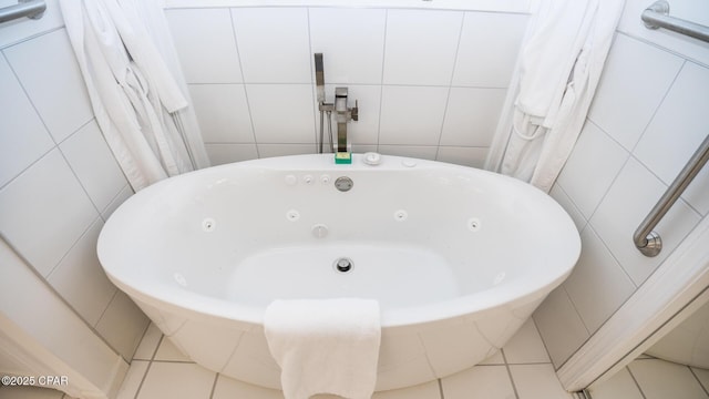 full bathroom with tile walls, a jetted tub, and tile patterned floors