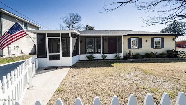 ranch-style home featuring a front lawn, fence, and a sunroom