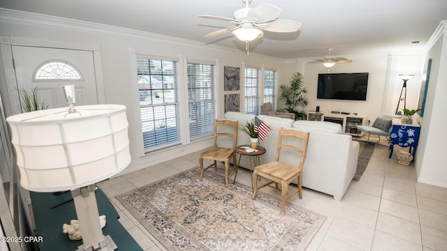 living area featuring ceiling fan, crown molding, baseboards, and light tile patterned floors