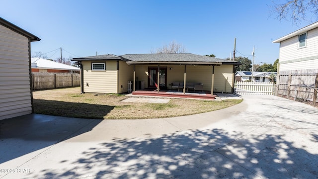 rear view of house featuring fence private yard, a lawn, concrete driveway, and a patio