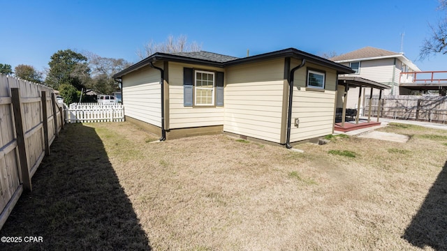 view of side of home with a fenced backyard and a lawn