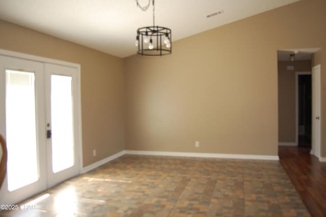 empty room featuring visible vents, baseboards, a chandelier, and french doors