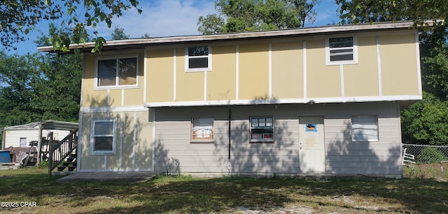 rear view of house with a lawn and fence