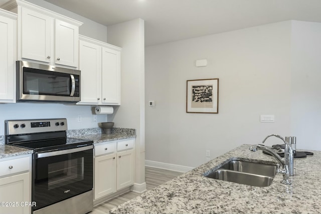 358 Sea Grove Way, Port St Joe, FL 32456 - kitchen with stainless steel appliances, light wood finished floors, white cabinetry, and light stone countertops