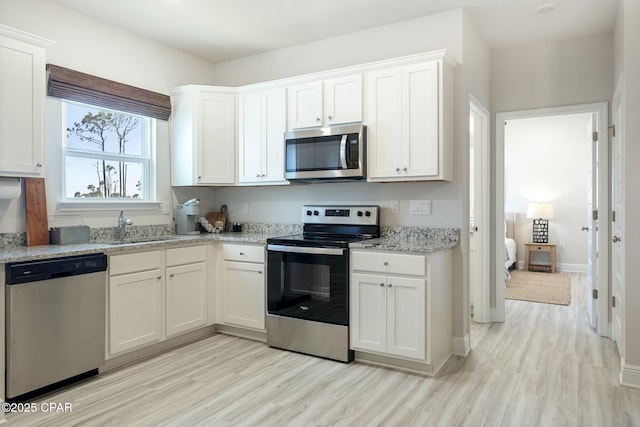 358 Sea Grove Way, Port St Joe, FL 32456 - kitchen with stainless steel appliances, light wood-type flooring, and white cabinetry