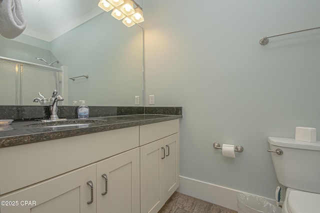 bathroom featuring baseboards, toilet, wood finished floors, a shower with shower door, and vanity