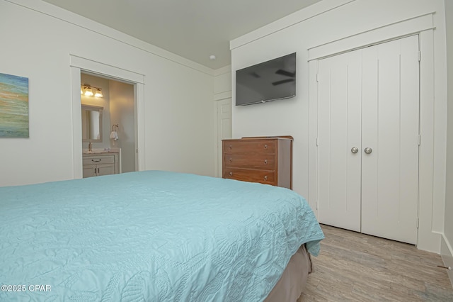 bedroom with ensuite bathroom, a closet, and light wood-style flooring