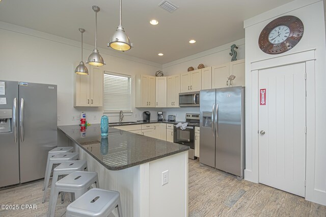 kitchen featuring visible vents, light wood-style flooring, appliances with stainless steel finishes, a sink, and a peninsula