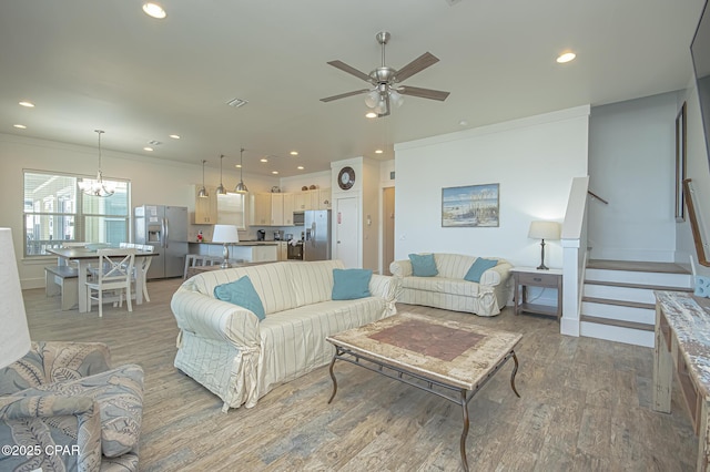 living room featuring recessed lighting, crown molding, light wood finished floors, and stairs