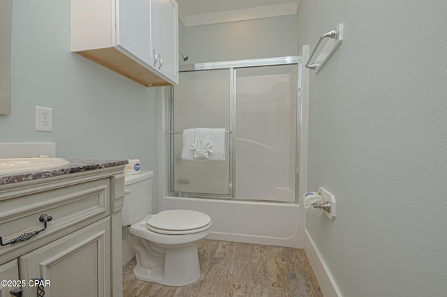 full bathroom featuring toilet, bath / shower combo with glass door, wood finished floors, and vanity