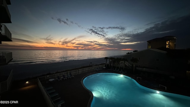 pool at dusk with a water view and a fenced in pool