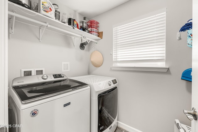 washroom featuring washing machine and dryer, laundry area, and baseboards