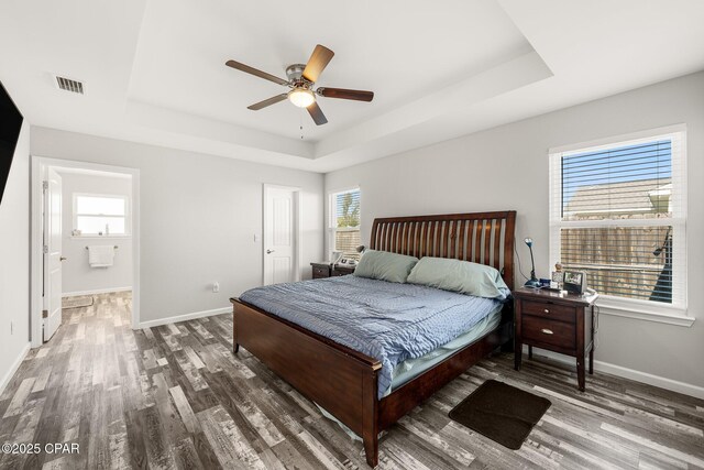 bedroom featuring multiple windows, a raised ceiling, and visible vents