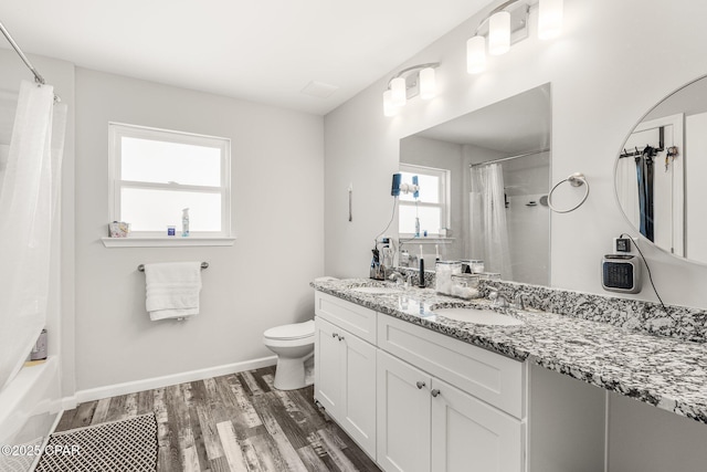 bathroom featuring baseboards, a sink, toilet, and wood finished floors