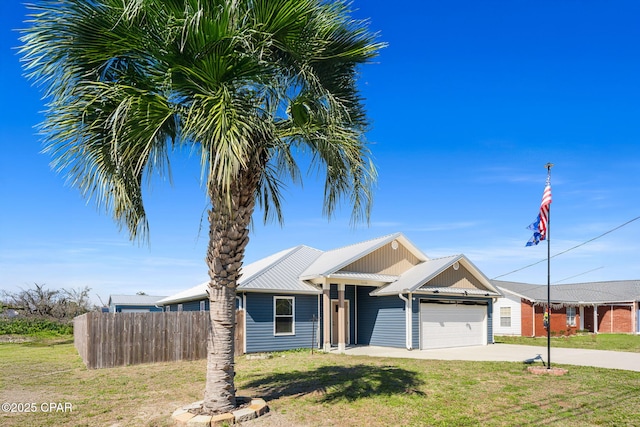 view of front of house with concrete driveway, fence, metal roof, a garage, and a front lawn