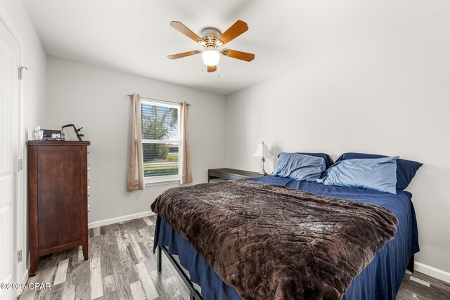 bedroom with ceiling fan, baseboards, and wood finished floors