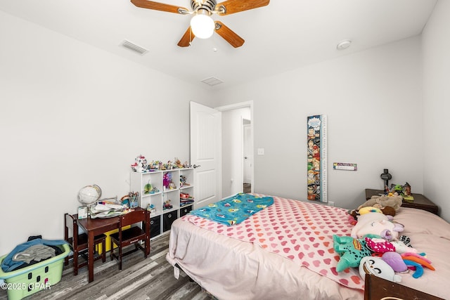 bedroom featuring a ceiling fan, visible vents, and wood finished floors