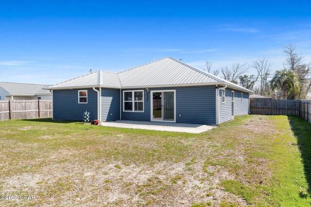 rear view of property with a patio area, a fenced backyard, metal roof, and a lawn