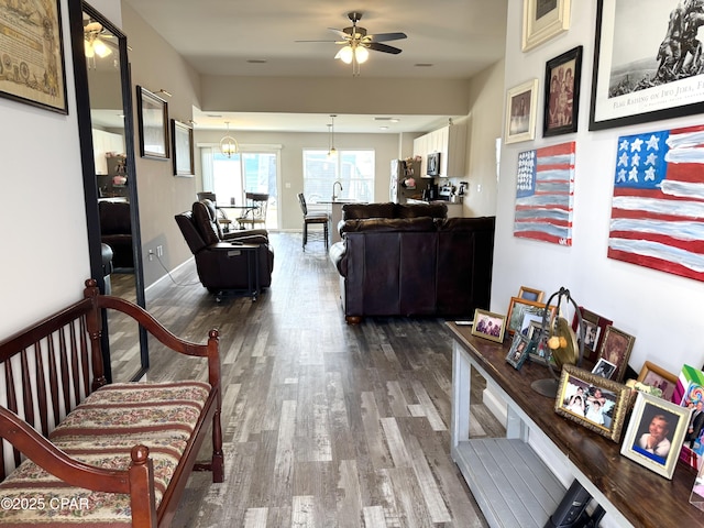 interior space featuring ceiling fan, wood finished floors, and baseboards