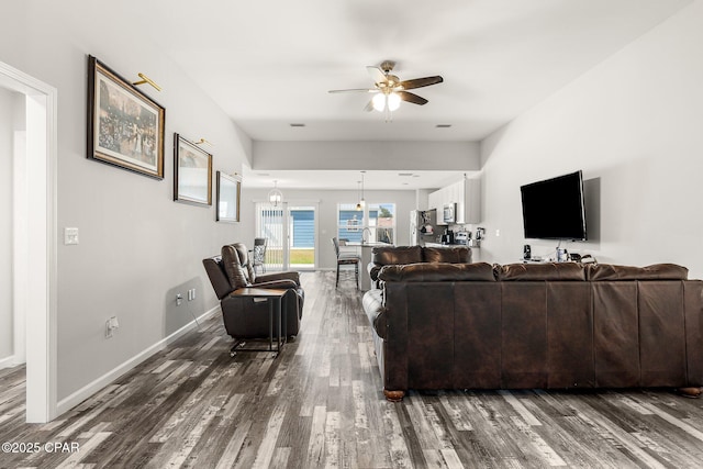 living area featuring dark wood-type flooring, ceiling fan, and baseboards