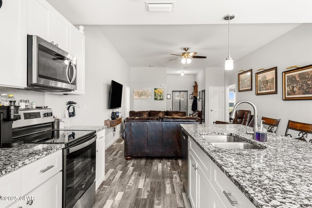 kitchen with stainless steel appliances, visible vents, white cabinetry, a sink, and wood finished floors