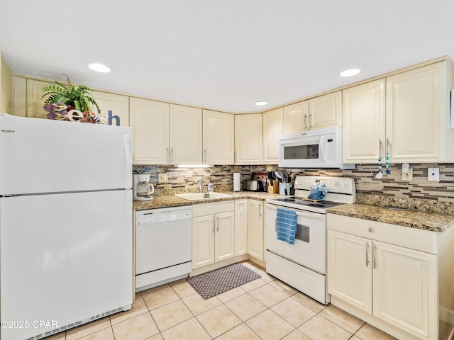 kitchen featuring white appliances, light tile patterned floors, tasteful backsplash, cream cabinets, and a sink