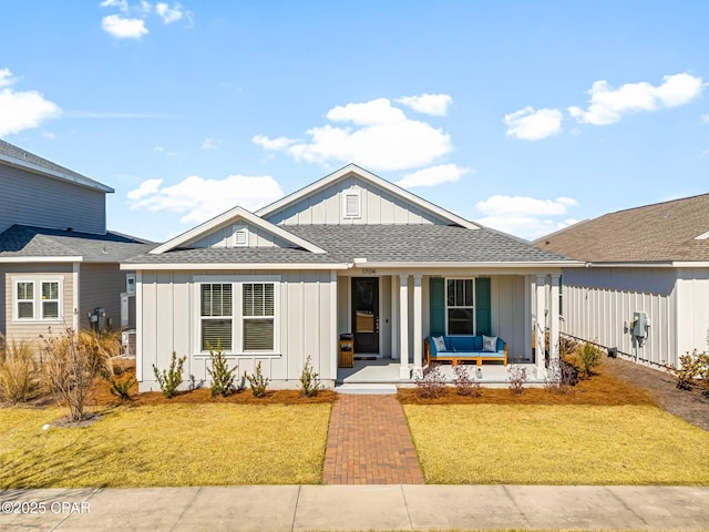 view of front of home featuring board and batten siding, covered porch, fence, and a front lawn