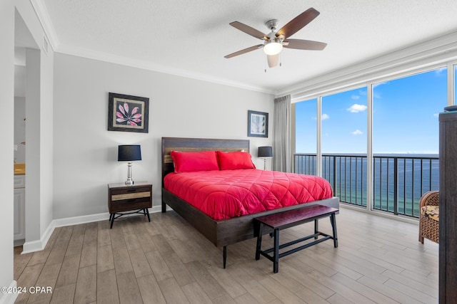 bedroom featuring access to outside, floor to ceiling windows, crown molding, and wood finished floors