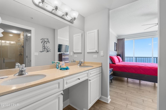 full bathroom featuring wood finished floors, a sink, a shower stall, and double vanity