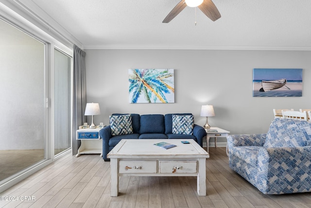 living area with light wood-style floors, ornamental molding, a textured ceiling, and a ceiling fan