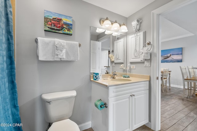 bathroom with baseboards, toilet, vanity, and wood tiled floor