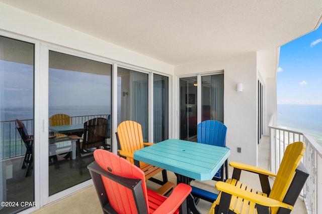 balcony with outdoor dining area and a water view
