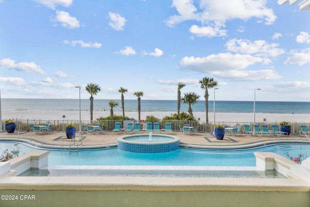 pool with a community hot tub, a patio, a water view, and fence