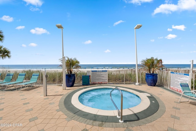 view of pool with a water view, a hot tub, fence, and a patio