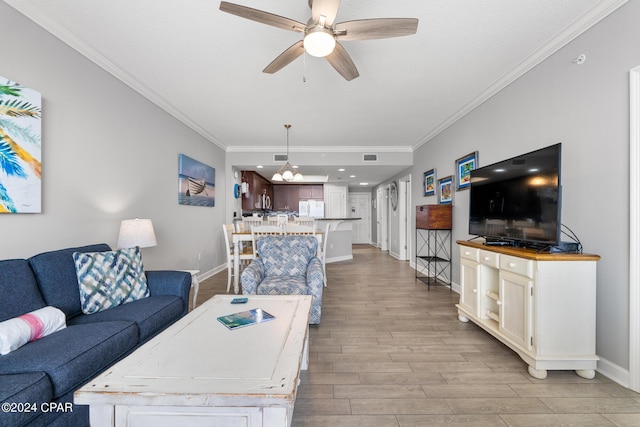 living area featuring baseboards, light wood-style flooring, ornamental molding, and a ceiling fan