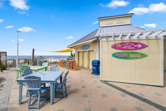 view of patio / terrace featuring outdoor dining space, an attached garage, fence, and a water view