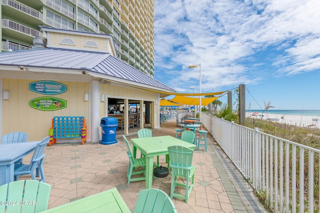 view of patio with outdoor dining space, a beach view, a water view, and outdoor dry bar