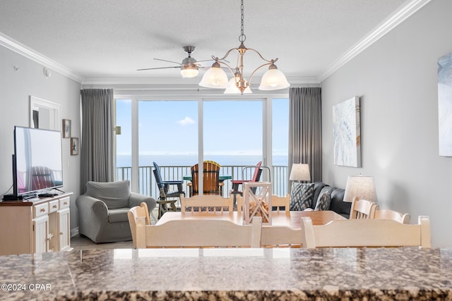 dining space featuring crown molding, ceiling fan with notable chandelier, a water view, and a textured ceiling